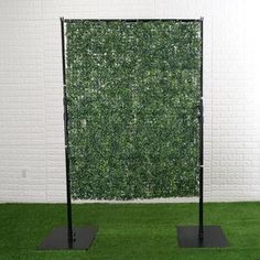 two black metal poles stand in front of a green wall with grass growing on it