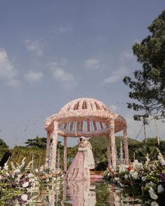 a bride and groom standing in front of a gazebo surrounded by flowers