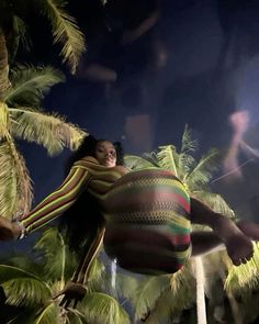 a woman is flying through the air with her arms spread out in front of palm trees