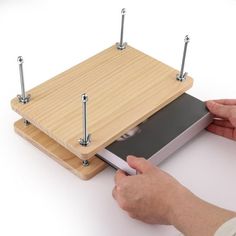 a person is holding an electronic device in front of a wooden board with nails on it