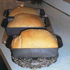 three loafs of bread sitting in pans on top of a counter next to each other