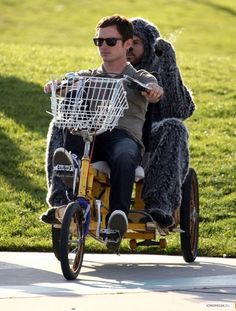 a man riding on the back of a bike while wearing a gorilla costume