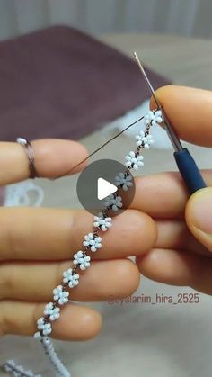 someone is working on something that looks like flowers and beads with a needle in their hand