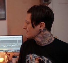 a man with tattoos sitting in front of a computer