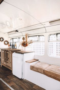 a kitchen area with a sink, refrigerator and window in the back side of a bus