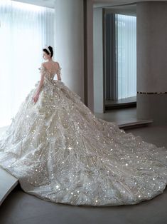 a woman in a white dress standing next to a large window with lights on it