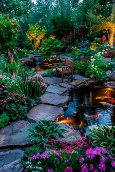 an outdoor pond surrounded by flowers and plants with lights on it's sides, in the middle of a garden