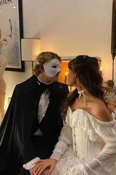 two people dressed up in costumes standing next to each other and one person wearing a mask