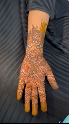 a person with henna on their hand and the arm is decorated with intricate designs