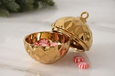 two gold bowls filled with candy canes next to a christmas tree ornament