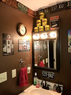 a bathroom with a sink, mirror and various signs on the wall above it's counter