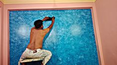 a man climbing up the side of a blue wall