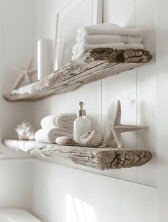 two wooden shelves holding towels, soap and other items in white bathroom with starfish