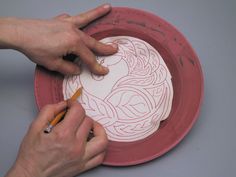 a person is drawing on a paper plate