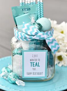 a mason jar filled with teal and white candies on top of a blue plate