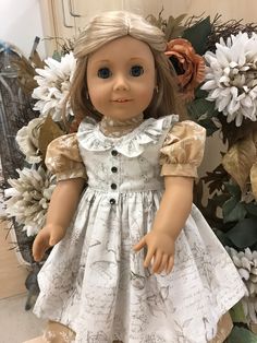 a doll with blonde hair and blue eyes wearing a white dress in front of flowers