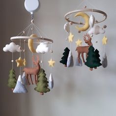 two mobiles with deer and stars hanging from the ceiling in front of a wall