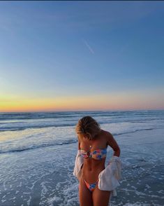 a woman standing on top of a beach next to the ocean