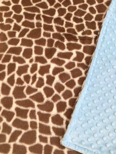 a giraffe print blanket laying next to a blue and brown dotty cloth