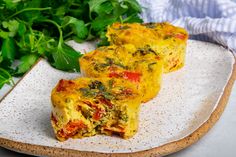 two pieces of vegetable quiche on a plate next to some parsley and greens