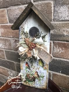 a birdhouse with some birds hanging from it's side on a brick wall