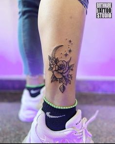 a woman's foot with a flower tattoo on her left leg and the moon in the background