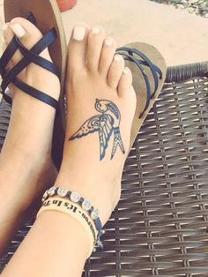 a woman's feet with a tattoo on her left foot and sandals on the other side