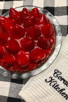 a dessert dish with strawberries in it on a checkered table cloth and napkin