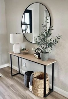 a mirror on the wall above a wooden table with a plant and basket underneath it