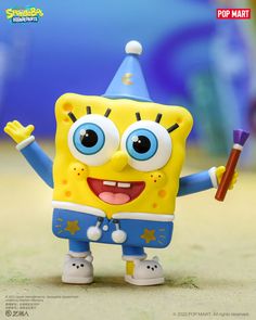 a yellow and blue toy with big eyes holding a stick in its hand on the ground