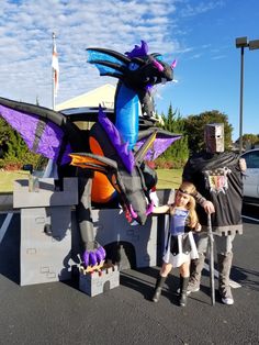 two people standing next to a dragon statue