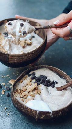 two coconut bowls filled with ice cream and chocolate chips, one being spooned into the bowl