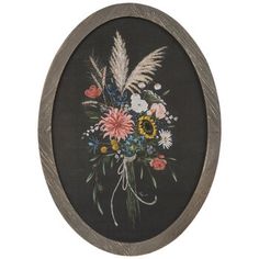 an oval frame with flowers and feathers painted on the side, hanging on a wall