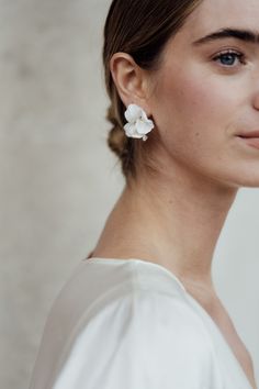 a woman wearing white earrings with a flower on it