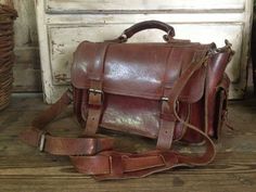 "Vintage Artisan Rustic Brown Leather Handbag Mini Briefcase ~~ c 1970s 2 side pockets with strap & buckle closures, 2 front strap and buckle closures. One pocket under the front flap. Silver hardware. Top leather carry handle that is studded in place. Adjustable and removable extra long carry strap to wear as a crossbody bag. Shoulder guard. Measures 12\" length, 14\" length including pockets, approx. 8\" height, approx. 6\" - 7\" depth including front pocket. Please check all measurements Travel Satchel Briefcase With Hasp Closure, Travel Briefcase Satchel With Hasp Closure, Retro Business Satchel With Detachable Strap, Travel Satchel Saddle Bag With Buckle Closure, Travel Saddle Bag With Buckle Closure, Everyday Satchel Saddle Bag With Buckle Closure, Travel Crossbody Saddle Bag With Buckle Closure, Retro Saddle Shoulder Bag With Detachable Strap, Travel Saddle Bag With Buckle Closure, Crossbody Style