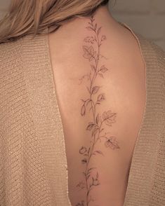 the back of a woman's neck with a vine tattoo on her left side