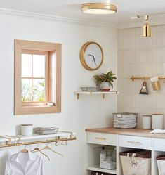 a kitchen with white walls and wooden floors, open shelving unit on the wall