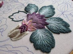 a close up of a piece of embroidery on a table cloth with flowers and leaves