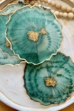 two green plates sitting on top of a wooden table next to beads and wood beads