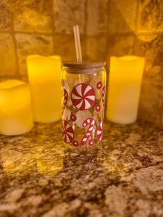 several candles and a glass with candy canes on it sitting on a counter top