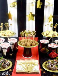 a table topped with cake and desserts covered in gold stars on top of red napkins