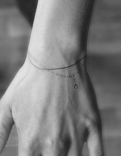 a person's hand with a small dotted line tattoo on the left side of their wrist