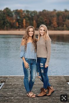 two women standing on a dock near the water