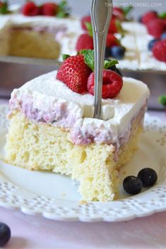 a piece of cake with berries on top and a fork stuck in the cake, ready to be eaten