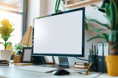 a computer monitor sitting on top of a desk next to a keyboard, mouse and plant