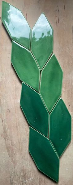 a close up of a green tile pattern on a wooden surface with no one around it