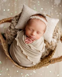 a newborn baby sleeping in a basket with white and silver glitters on the floor