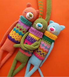 three knitted stuffed animals laying next to each other on top of an orange surface