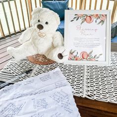 a white teddy bear sitting on top of a table next to a sign and envelope