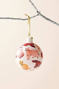 a christmas ornament hanging from a tree branch with animals painted on the ornaments